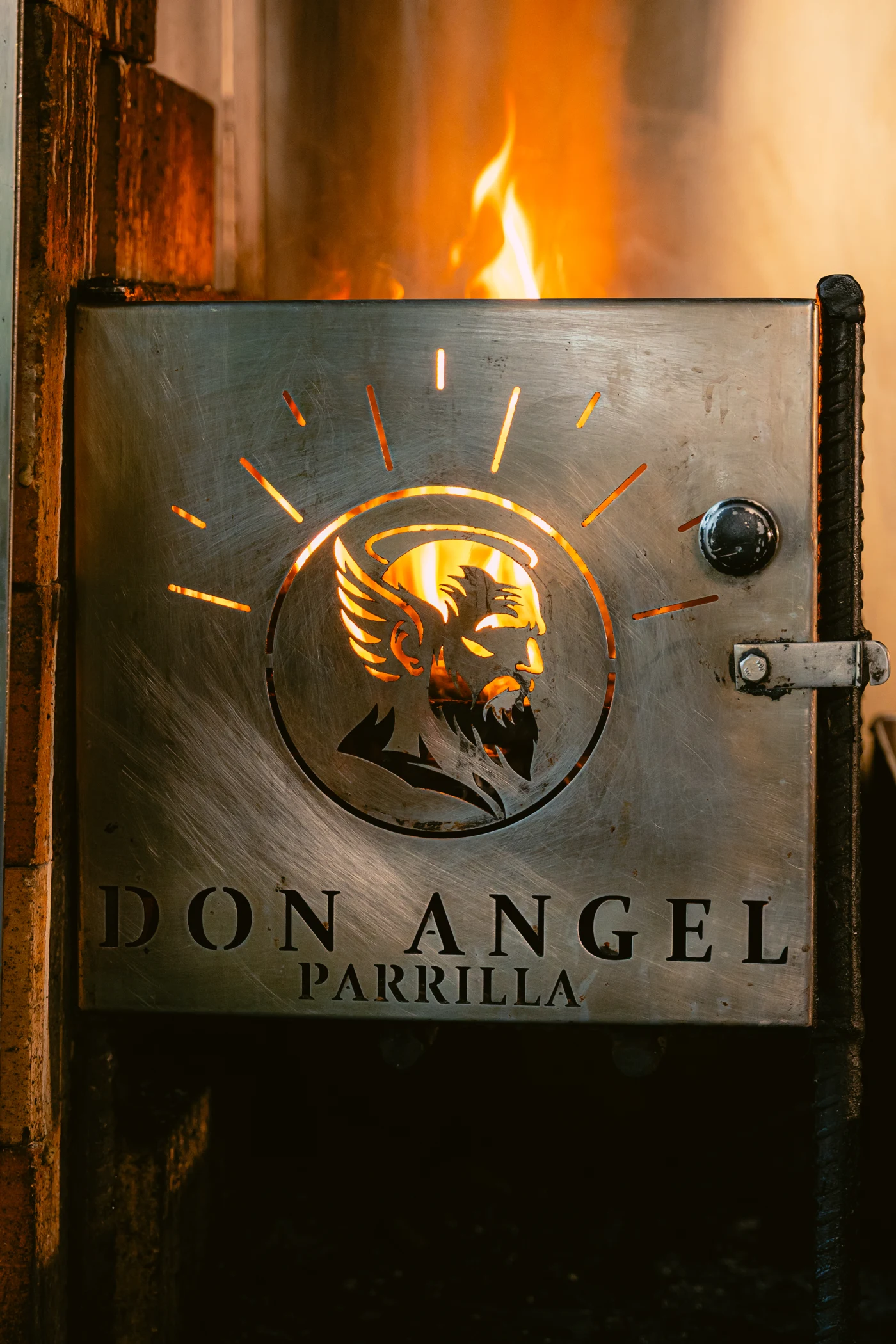 Fuego y emblema de Don Ángel en la parrilla