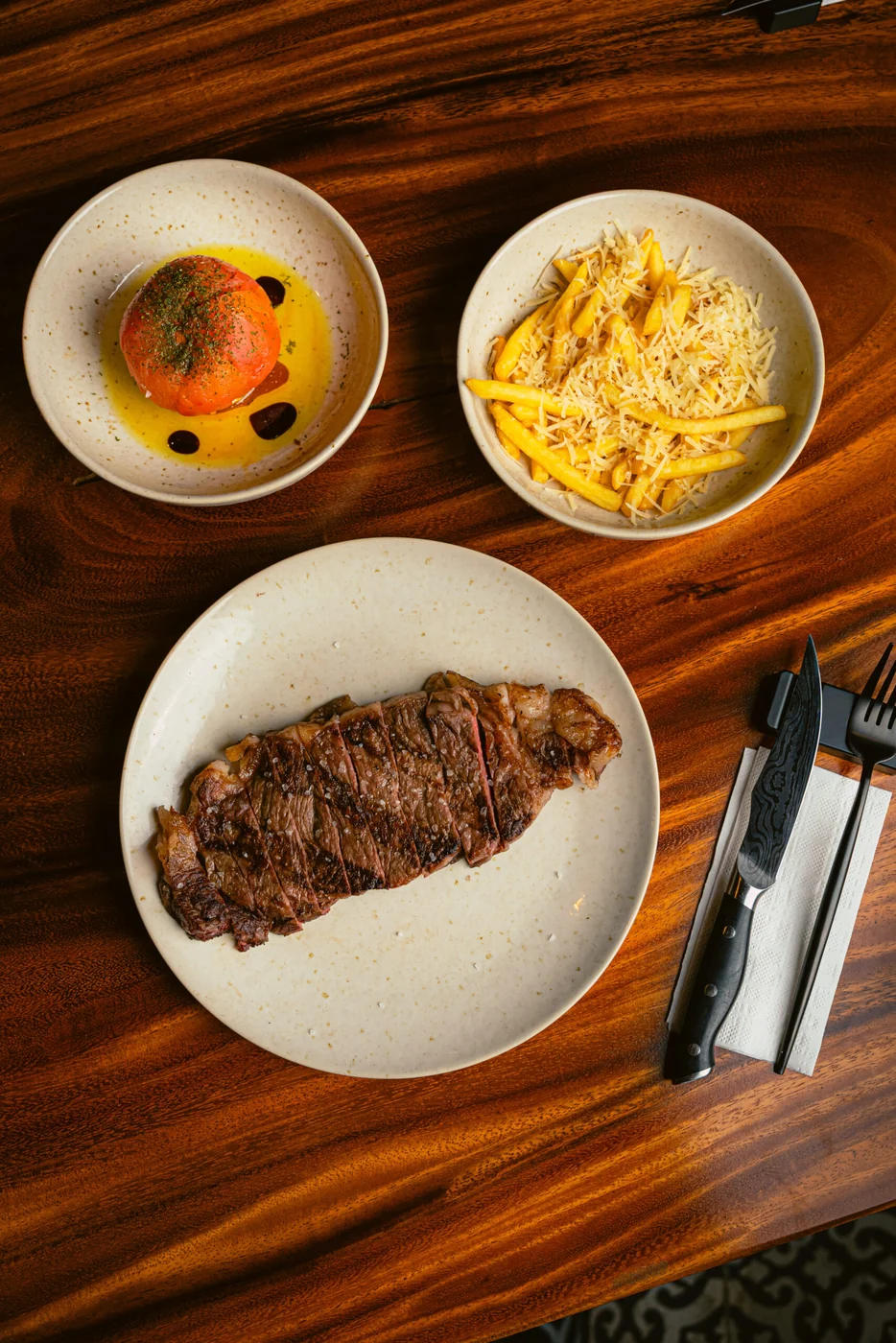Corte de carne servido con papas a la francesa y acompañamientos