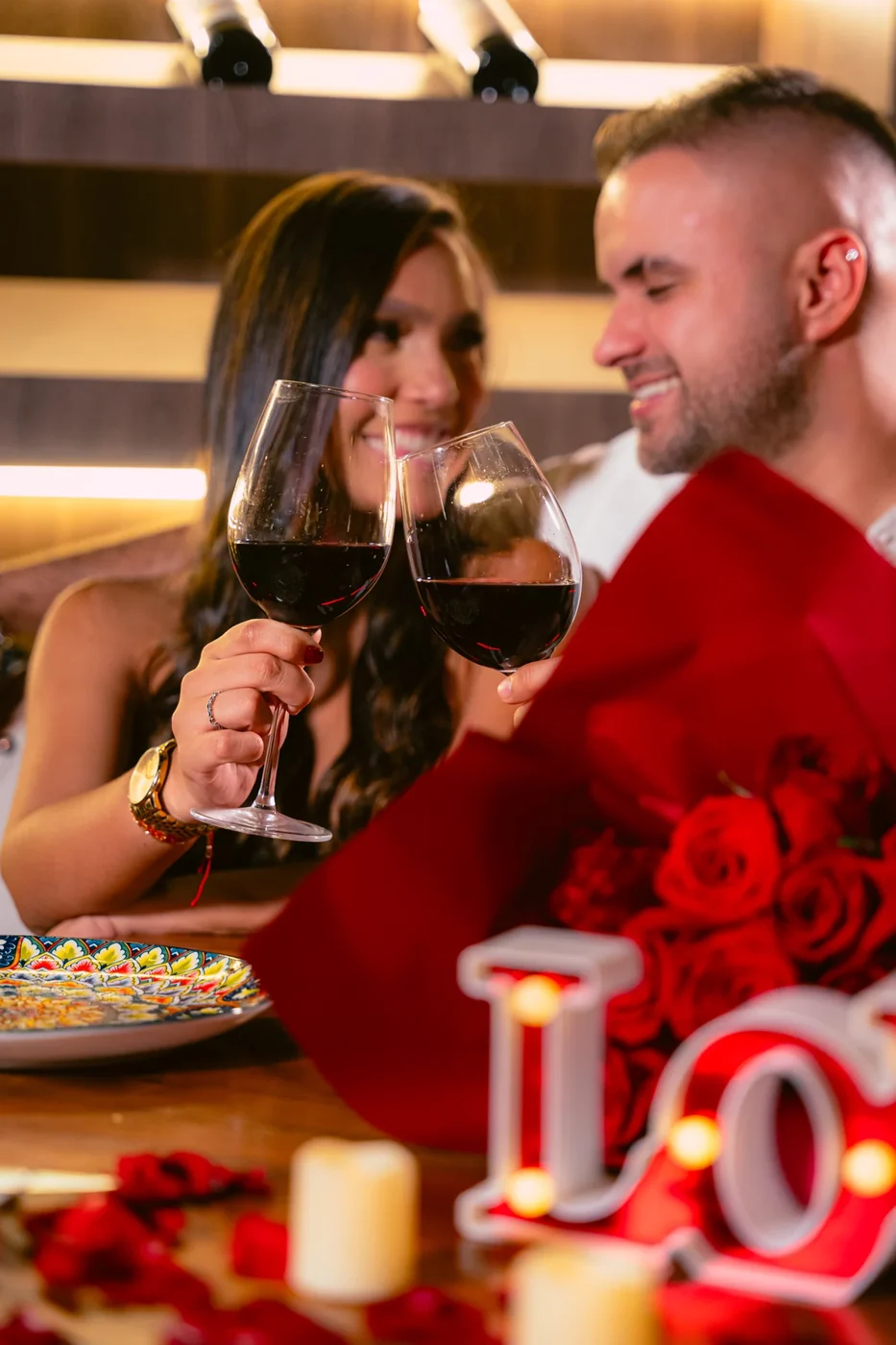 Pareja brindando con vino junto a rosas en Don Ángel