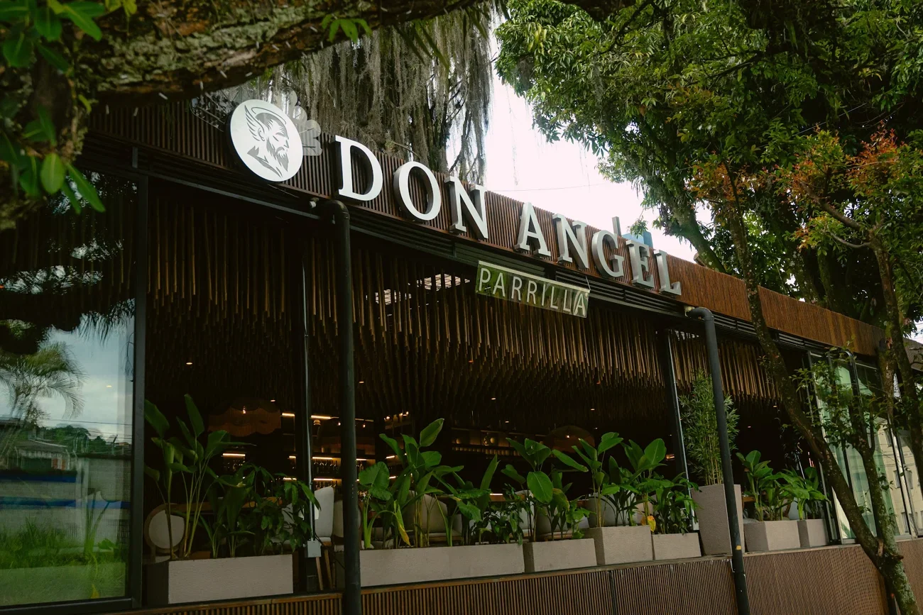 Fachada de Don Ángel Parrilla con su letrero entre árboles